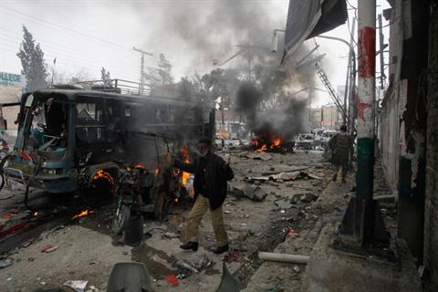 A policeman calls for help as he stands near a burning site after a bomb blast in Quetta.jpg