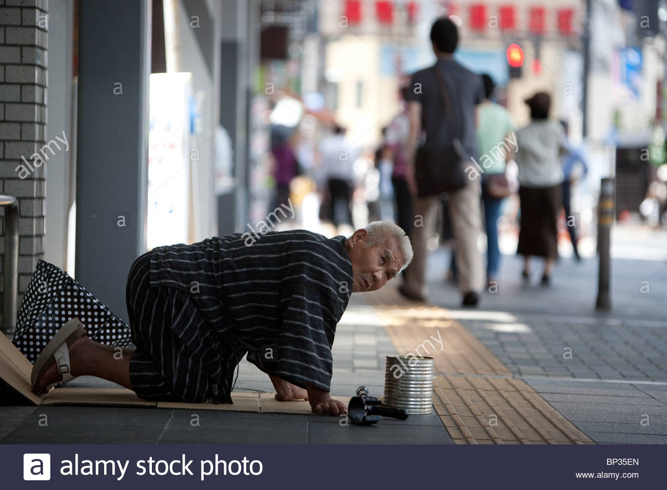 elderly-male-pensioner-kneels-in-the-street-begging-for-money-in-a-BP35EN.jpg