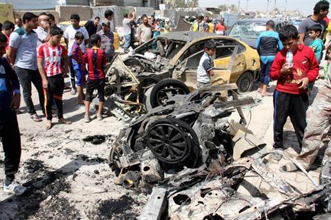 Residents look at wrecked cars at the site of a car bomb attack in Sadr City in Baghdad April 9.jpg