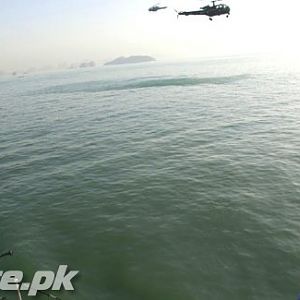 A Pakistan Navy soldier (L) operates an anti-aircraft weapon as helicopters