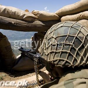 Soldier aiming his weapon on top of a mountain