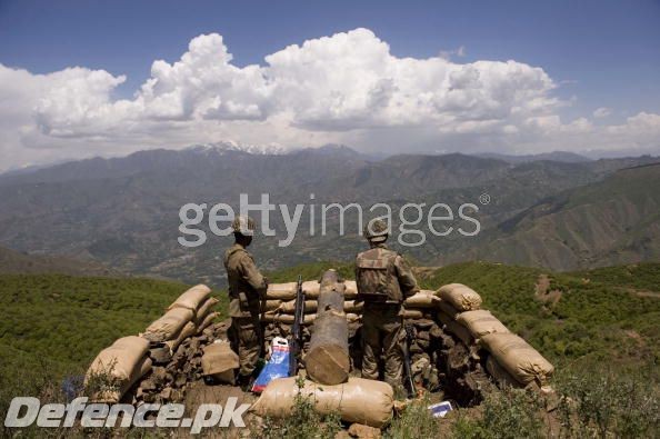 Soldiers stand guard on top of a mountain