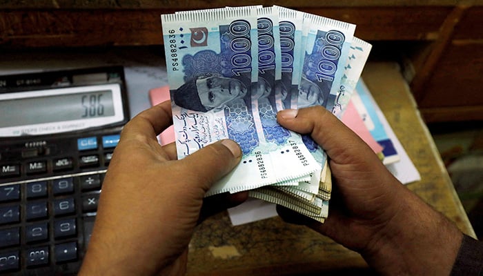 A trader counts Pakistani rupee notes at a currency exchange booth in Peshawar, Pakistan December 3, 2018. — Reuters/ File