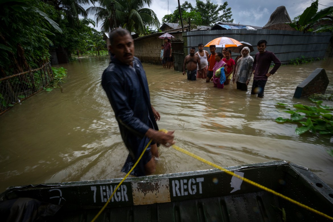 Indian army personnel rescue flood affected villagers on a boat in Jalimura village