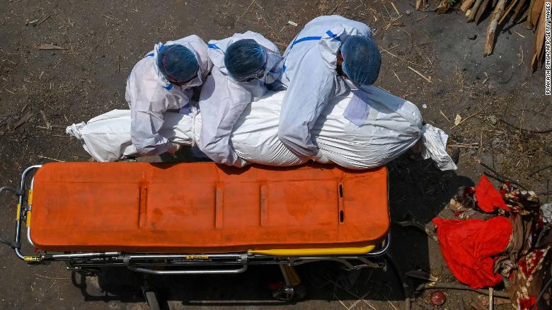 Family members and ambulance workers in protective equipment carry the body of a victim who died of the Covid-19 coronavirus at a cremation ground in New Delhi on April 27, 2021.