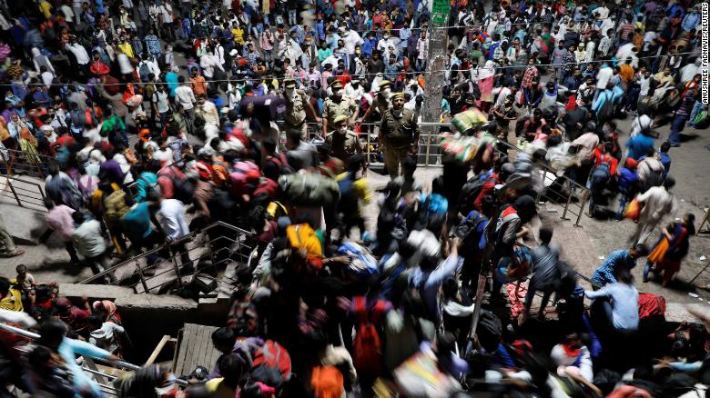 Police officers stand by as migrant workers scramble inside a bus station in Ghaziabad, India, on Saturday, March 28.