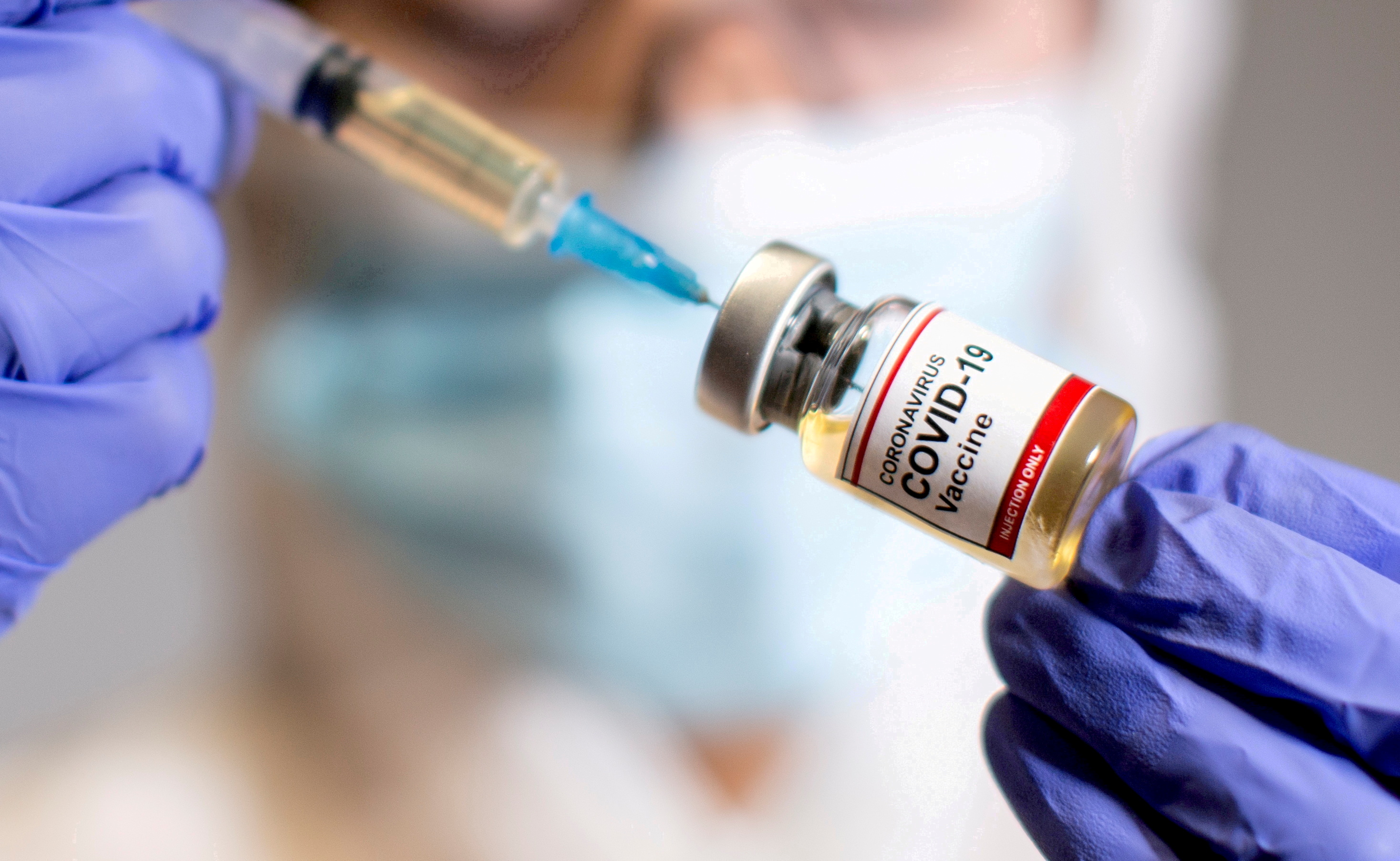 A woman holds a small bottle labelled with a Coronavirus COVID-19 Vaccine sticker and a medical syringe in this illustration taken  October 30, 2020. REUTERS/Dado Ruvic