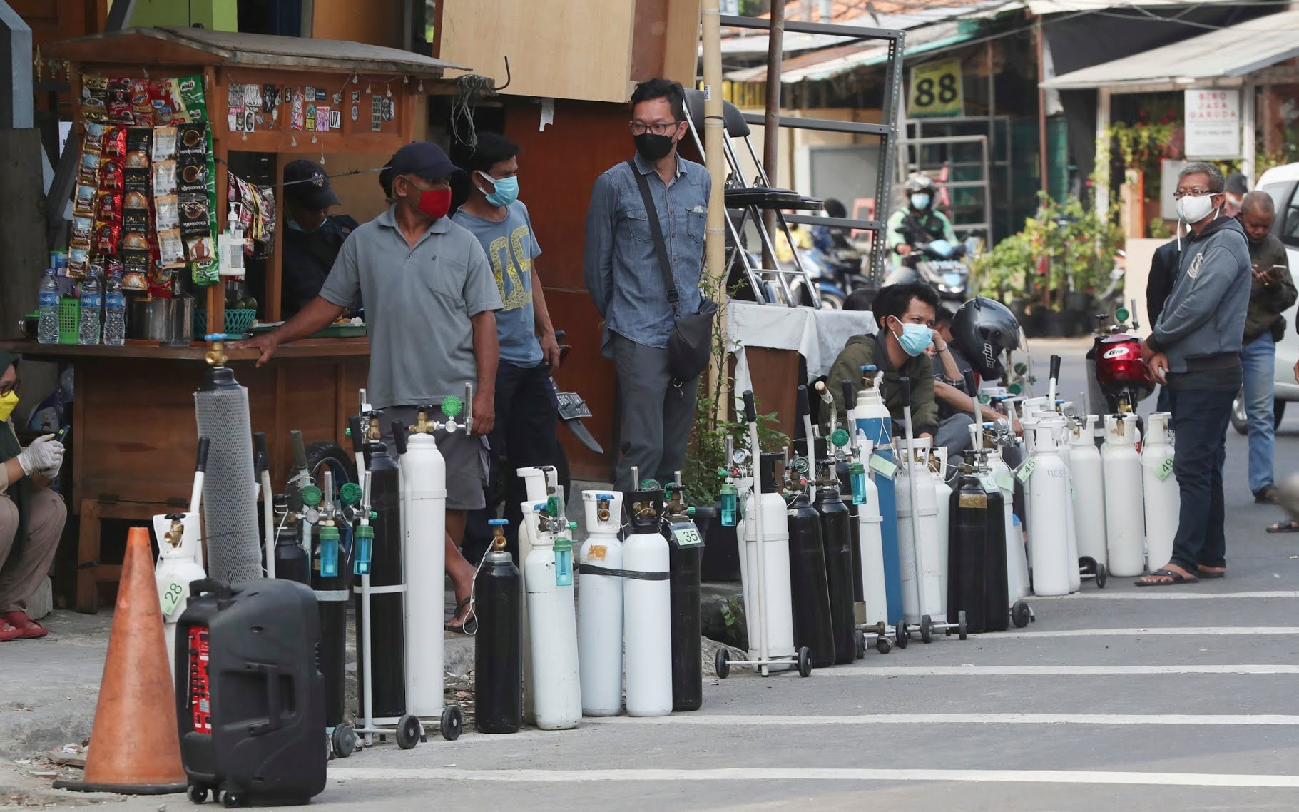 People queue to refill oxygen tanks at a filling station in Jakarta as hospitals grapple with soaring infections