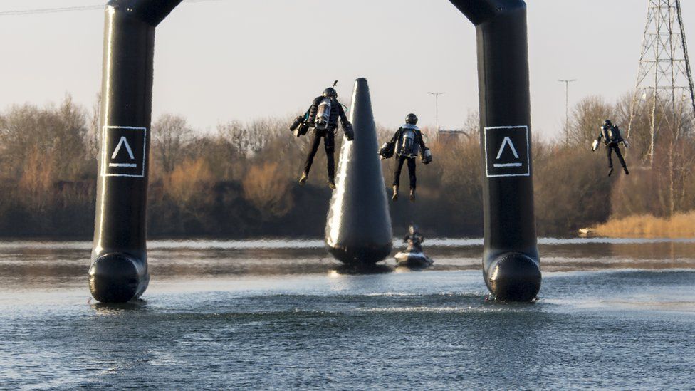 Three people wearing Gravity Industries jetpacks