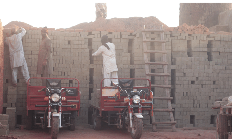 Labourers stacking bricks in a zig-zag pattern.