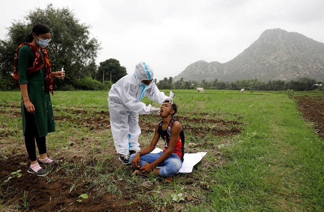 healthcare worker hemaben raval collects a swab for a rapid antigen test from farmer vinod vajabhai dabhi in his field during a door to door vaccination drive amid the ongoing coronavirus disease covid 19 outbreak in banaskantha district in the western state of gujarat india july 23 2021 photo reuters