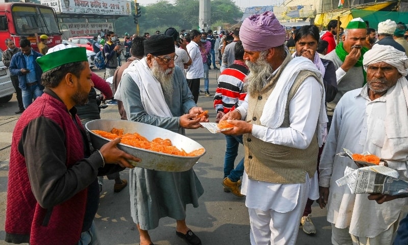 Farmers distribute sweets to celebrate after India's Prime Minister announced to repeal three agricultural reform laws that sparked almost a year of massive protests by farmers around the country in Ghaziabad on November 19. — AFP