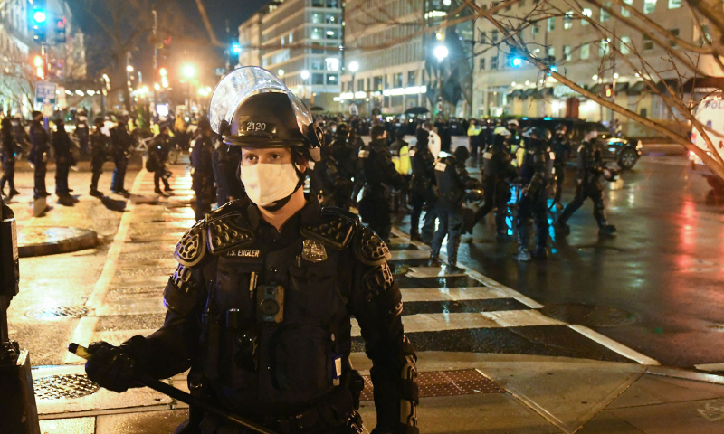 A police officer in riot gear stands guard as protesters gather near Black Lives Matter Plaza during a protest on Decr 12 in Washington, United States. — AFP