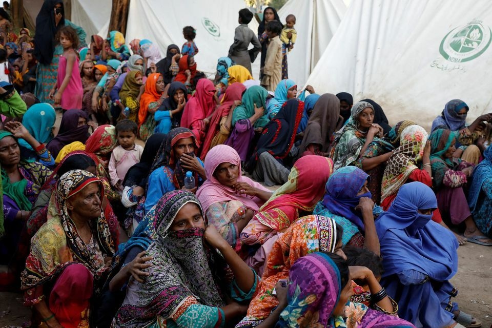 Women displaced because of the floods wait to receive food handouts while taking refuge in a camp, in Sehwan, Pakistan. Photo: Reuters