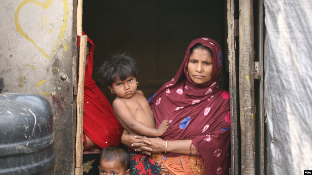 FILE - Rohingya refugee Jomila Begum stands with two of her eight children, at her shack inside a Rohingya refugee colony in Jammu city, north India, April 12, 2022. Jomila’s husband was picked up by Indian police and sent to jail, recently, after being charged with illegal entry into India. (Mir Imran/VOA)