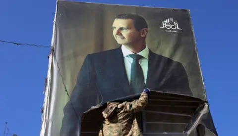 Getty Images A rebel fighter tears down a portrait of Syria's President Bashar al-Assad in Aleppo, after it was captured by Hayat Tahrir al-Sham and its allies on 30 November 2024