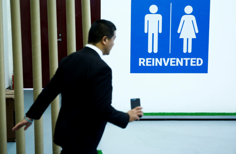 A man walks past a toilet sign at the Reinvented Toilet Expo showcasing sewerless sanitation technology in Beijing (photo credit: REUTERS)