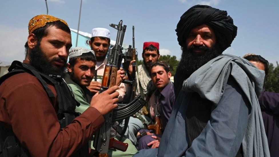 Talban militants with guns on back of a pickup truck