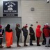 Women wait in a long line for a restroom at a sports stadium.