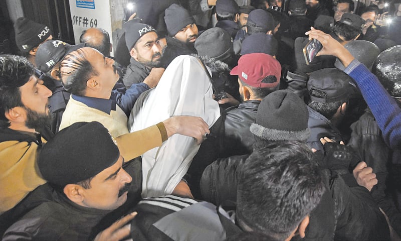 <p>ISLAMABAD: Police officials escort former information minister Fawad Chaudhry (centre) with his head covered in white cloth, as he is presented before a court here, on Wednesday night. —Online</p>