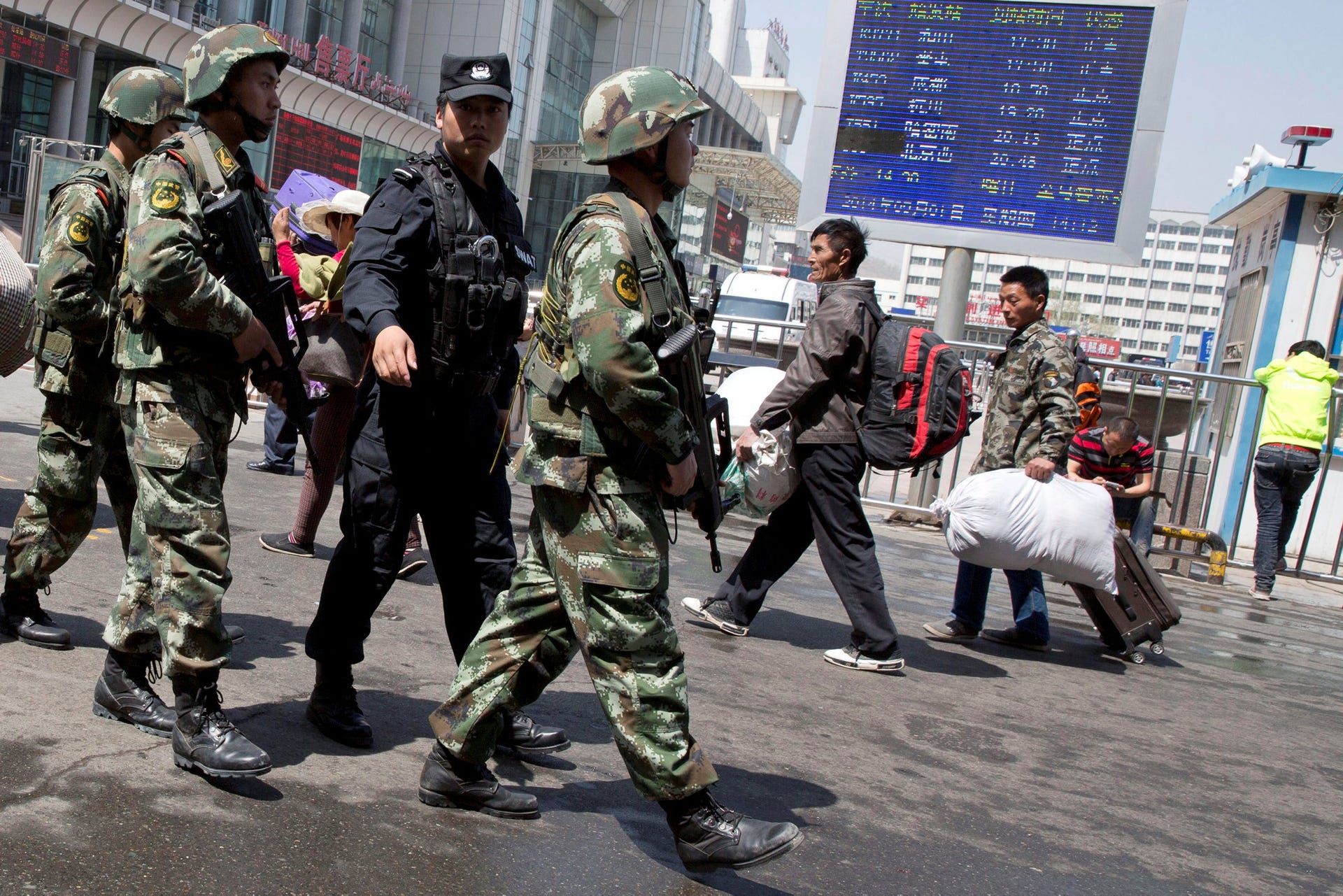 Armed Chinese paramilitary policemen marching past the site of the explosion outside the Urumqi South Railway Station in Urumqi, Xinjiang, May 1, 2014.