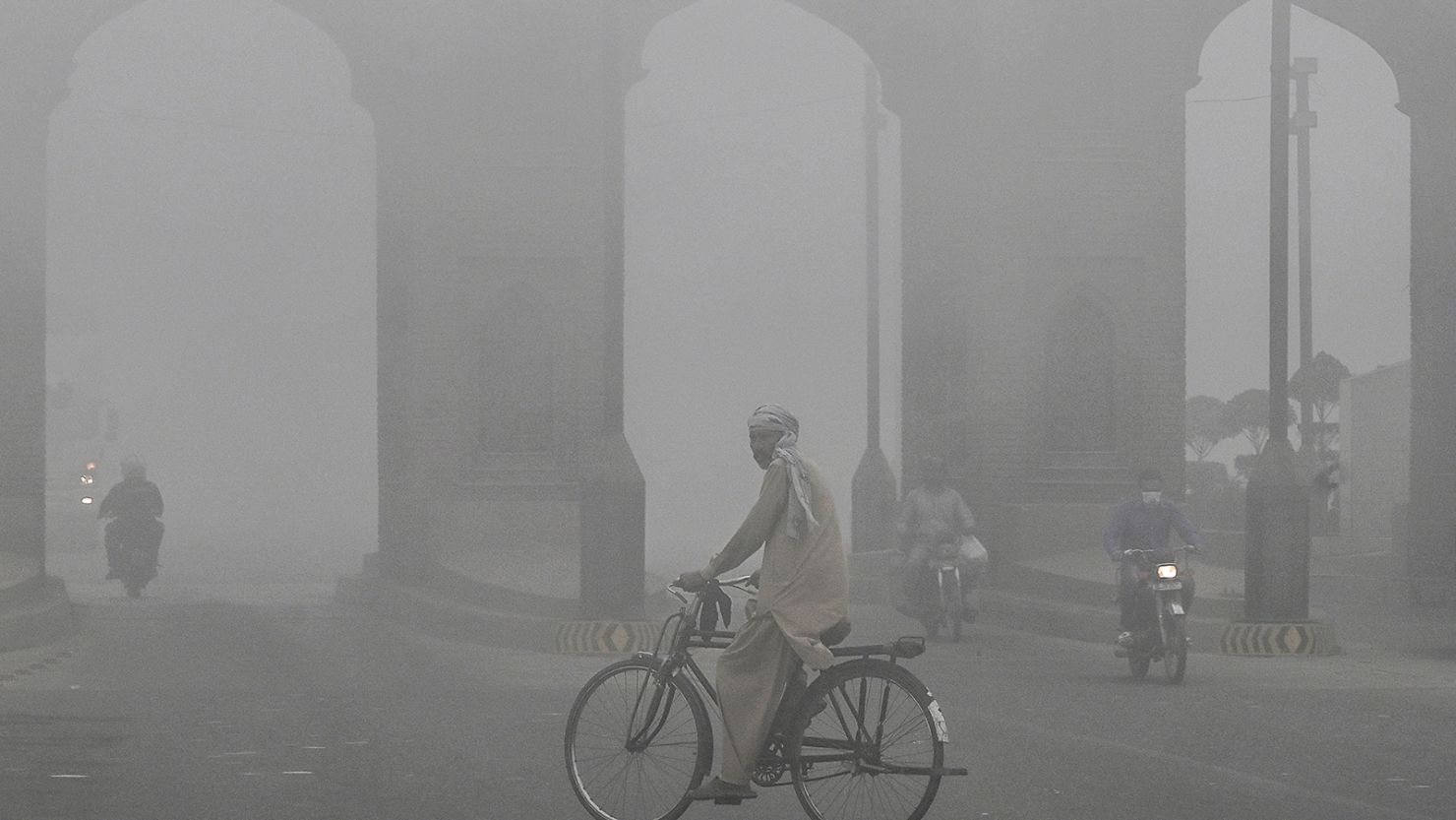 A cyclist rides along a street engulfed in thick smog, in Lahore on November 10, 2024.