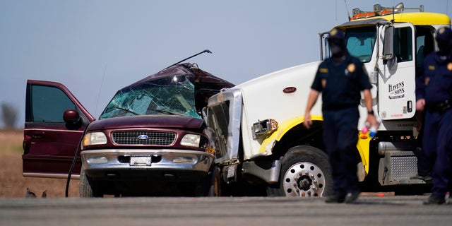 Law enforcement officers work at the scene of a deadly crash in Holtville, Calif., on Tuesday, March 2, 2021. Authorities say a semi-truck crashed into an SUV carrying 25 people on a Southern California highway, killing at least 13 people. (AP Photo/Gregory Bull)