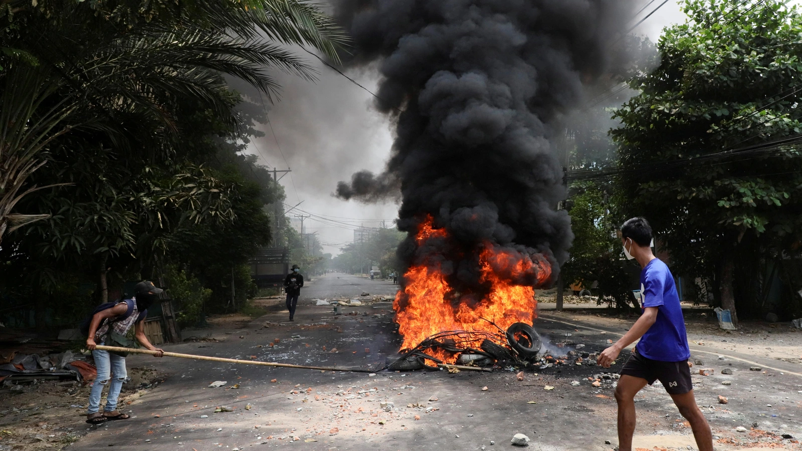 An anti-coup protester walks past burning tires after activists launched a garbage strike against the military rule, in Yangon, Myanmar March 30, 2021.