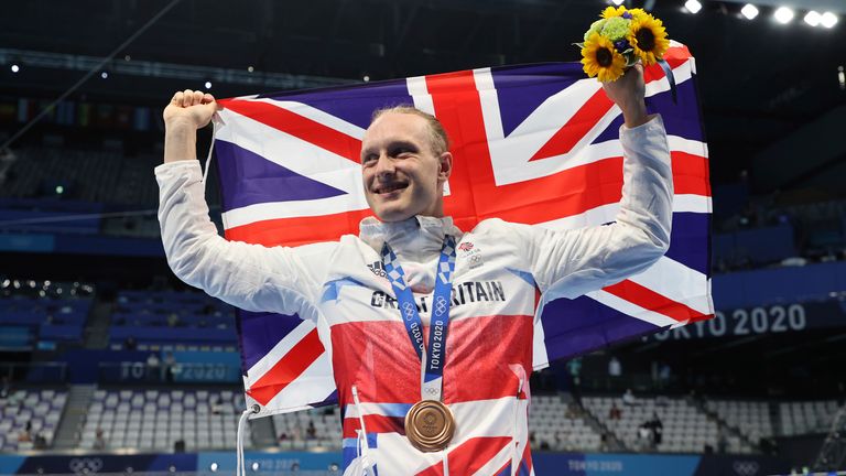 Greenbank raises the Union Jack flag and collects the bronze medal following the men's 200m backstroke final