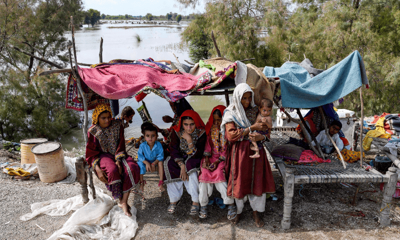 A flood-affected family rests in a makeshift shelter following heavy monsoon rains on the outskirts of Larkana, Sindh on Aug 31, 2024. — AFP