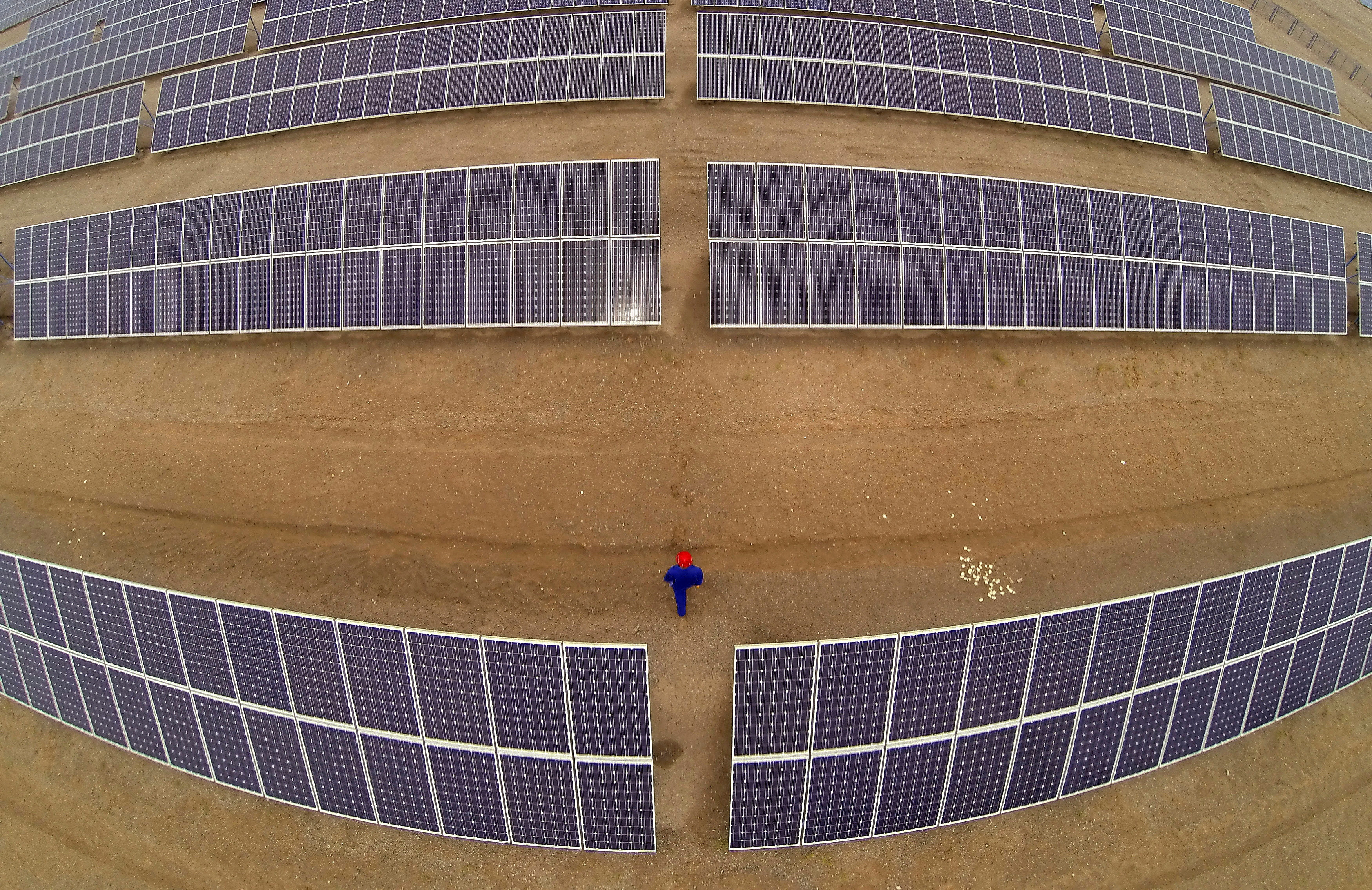 A worker inspects solar panels at a solar farm in Dunhuang