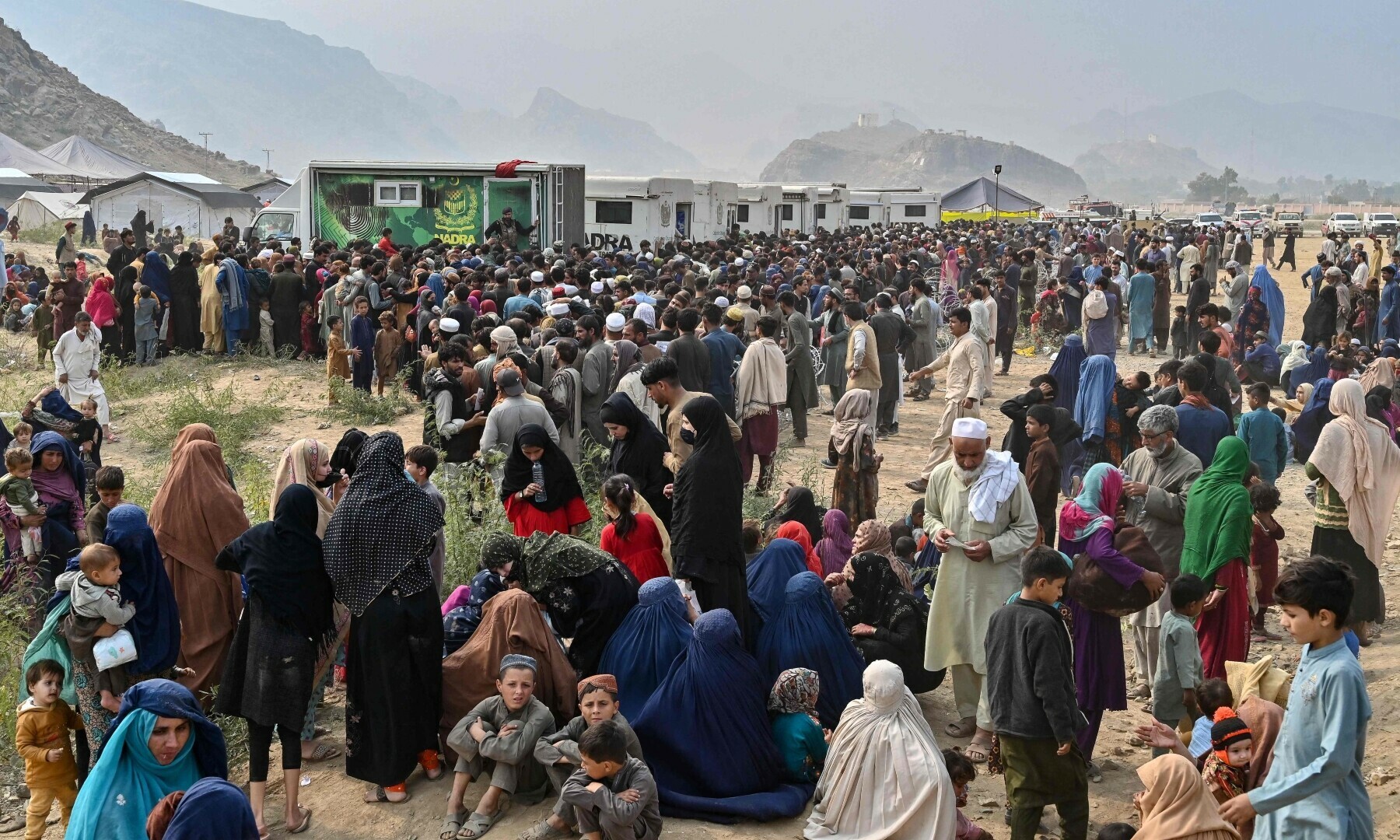 Afghan refugees gather around National Database and Registration Authority (Nadra) vans for biometric verifications as they prepare to depart for Afghanistan, at a holding centre in Landi Kotal on Nov 1. — AFP