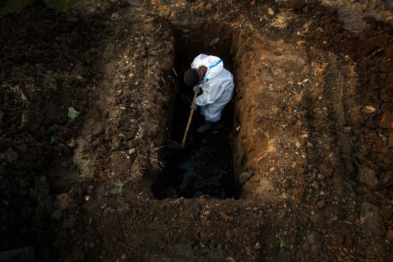 In this April 25, 2021 photo, a man in protective suit buries the body of a person who died of COVID-19 in Guwahati, India [File: Anupam Nath/AP]