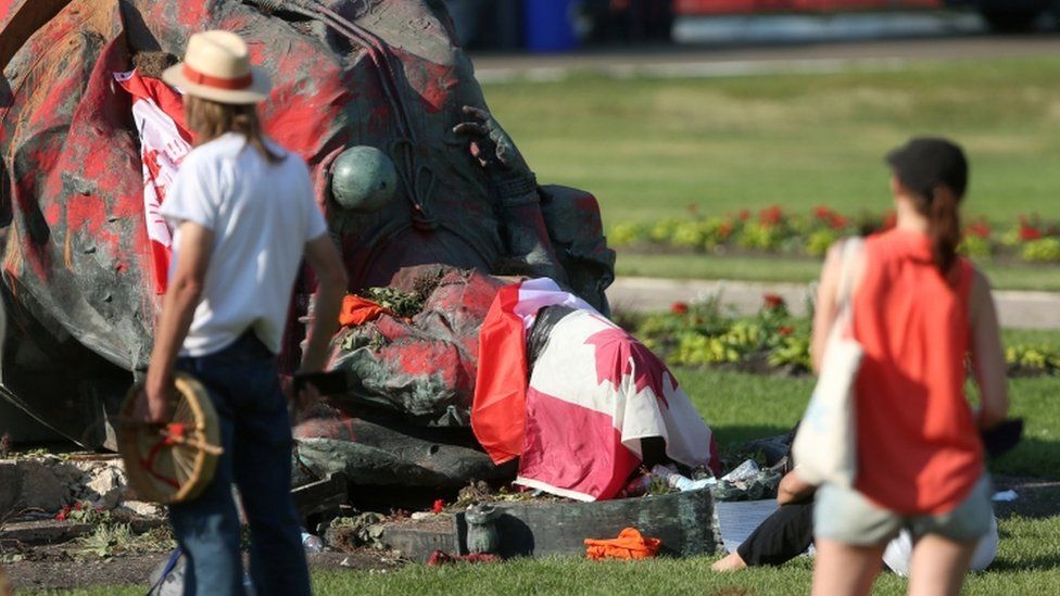 A statue of Queen Victoria lies upended on the floor