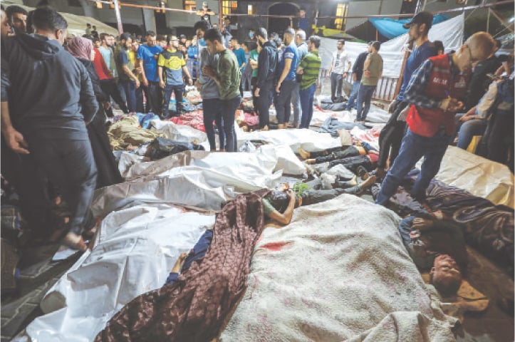  People gather around bodies of Palestinians killed in Israeli air strikes on a hospital in Gaza Strip, on Tuesday.—AFP 