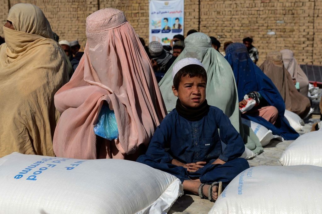 A group of women and a child wait for food grains from World Food Programme