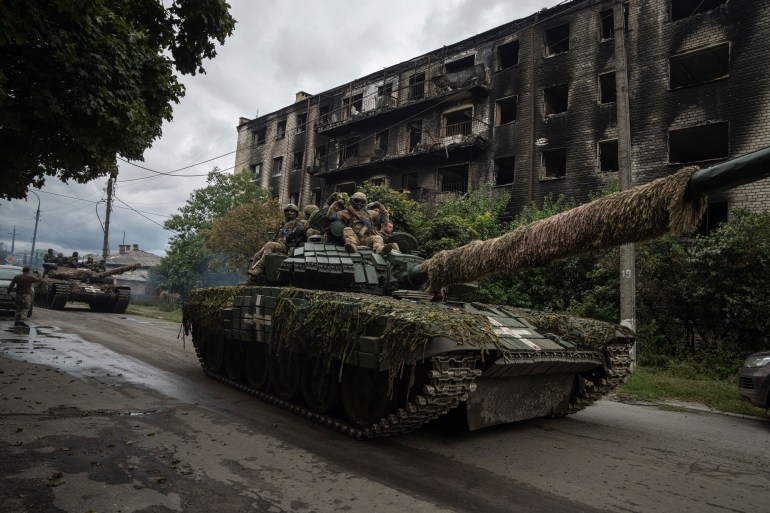 Ukrainian servicemen drive atop a tank in Izyum