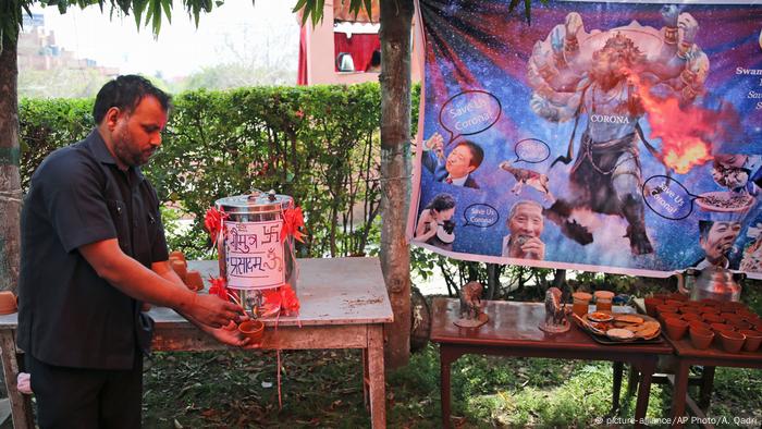 An Indian Hindu man pours cow urine in a cup during an event organized by a Hindu religious group to promote consumption of cow urine as a cure for the new coronavirus in New Delhi, India