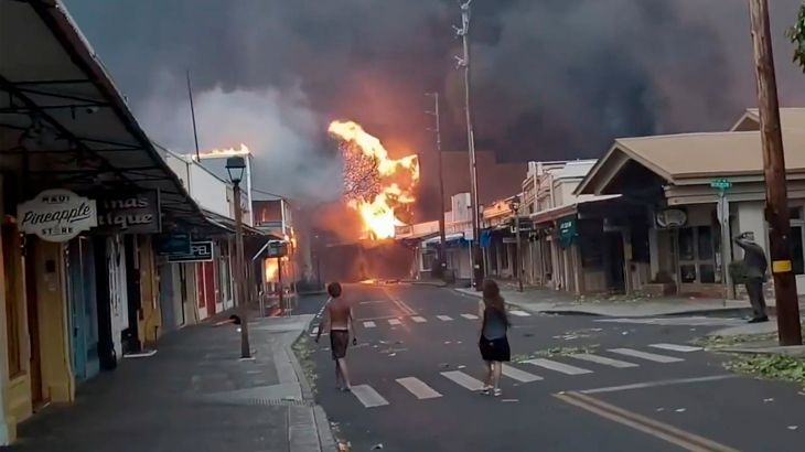 People watch as smoke and flames fill the air from raging wildfires on Front Street in downtown Lahaina, Maui