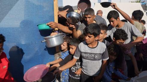 Displaced Palestinians, who fled their houses amid Israeli strikes, wait at a food distribution point as they shelter in tents set up in a United Nations-run center, following Israel's call for more than 1 million civilians in northern Gaza to move south, in Khan Yunis, in the southern Gaza Strip on October 26, 2023, amid the ongoing battles between Israel and the Palestinian group Hamas.