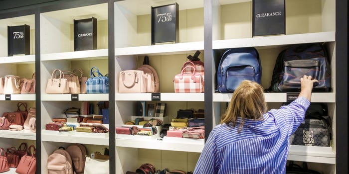 A woman reaches for a bag at a Coach store.