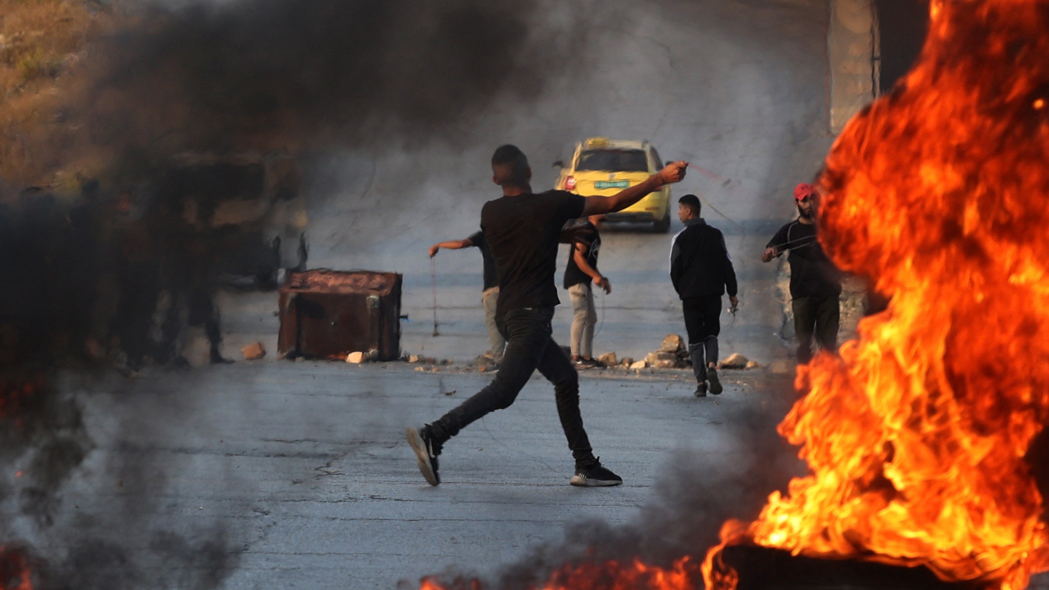 A Palestinian demonstrator throws rocks towards Israeli soldiers during clashes in the city of Ramallah in the occupied...