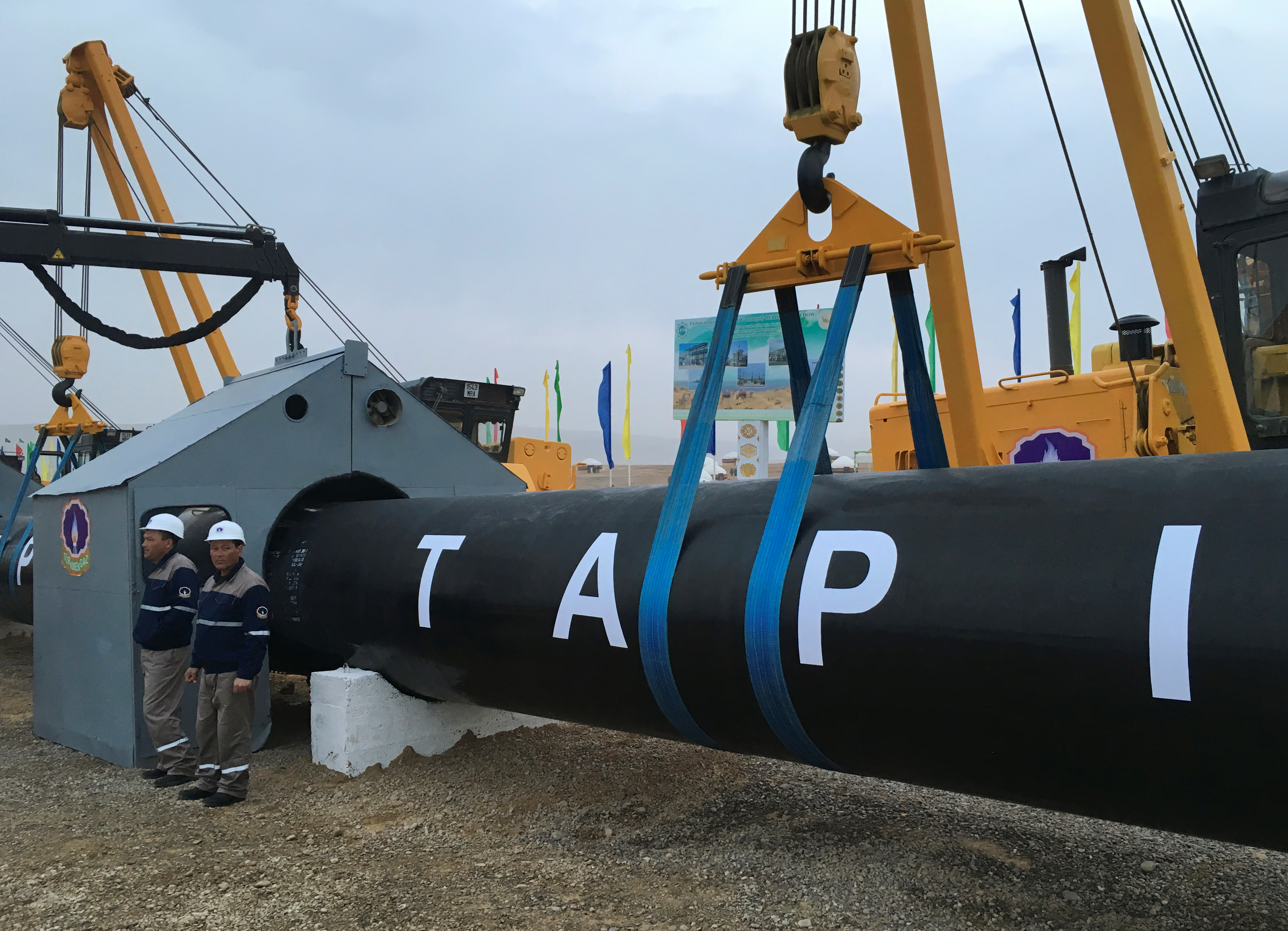 Workers stand near a gas pipe during the launching ceremony of construction work of the TAPI project on the Afghan section of a natural gas pipeline that will link Turkmenistan through Afghanistan to Pakistan and India, near the town of Serhetabat, Turkmenistan February 23, 2018. REUTERS/Marat Gurt