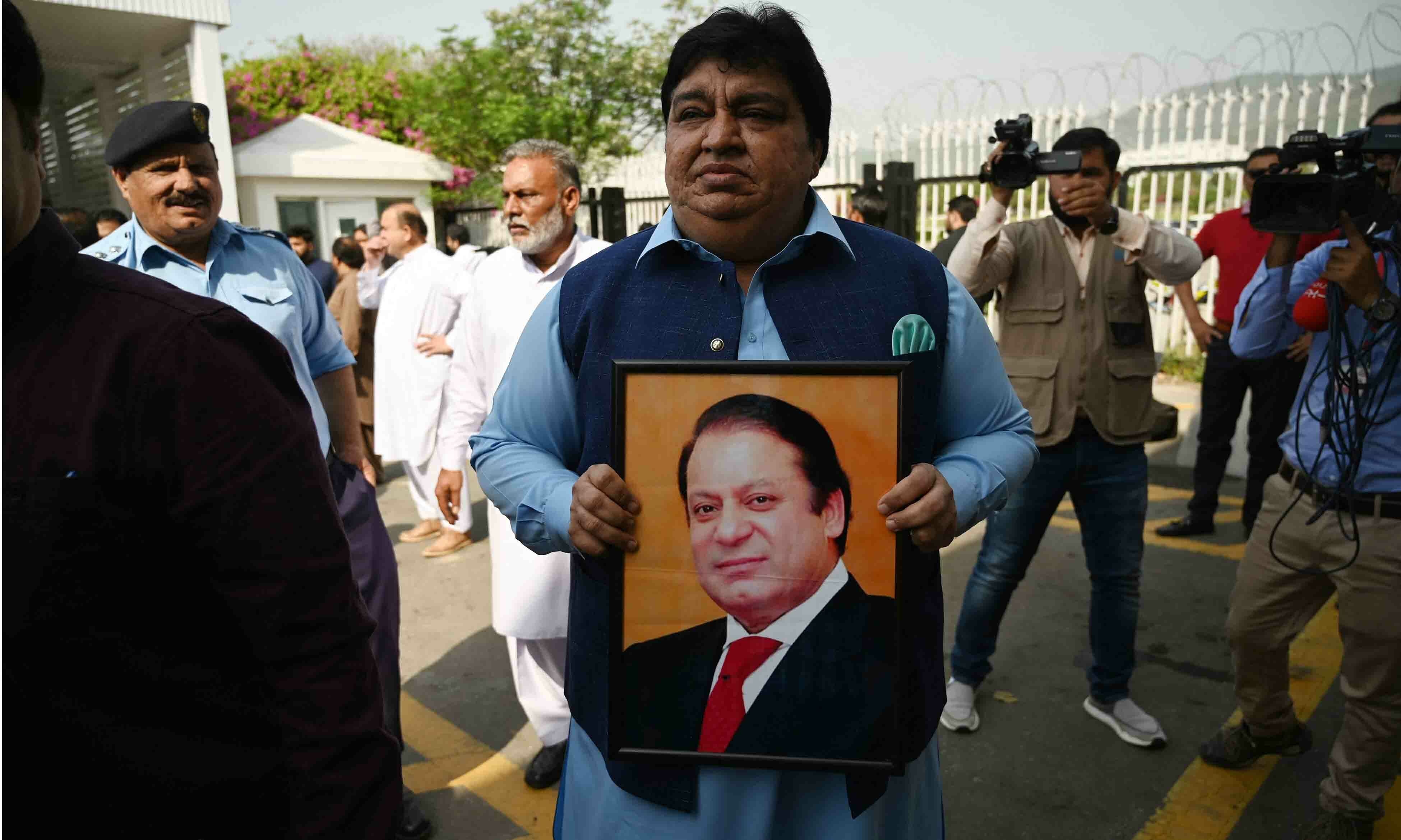 MNA Kesoo Mal Khel Das holds a picture of former Pakistan's Prime Minister Nawaz Sharif as he arrives at the Parliament House building in Islamabad on April 3. — AFP