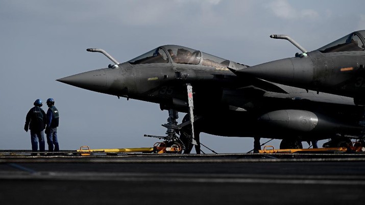 Crewmen of French aircraft carrier Charles de Gaulle stand on deck next of Rafale fighter jets, off the coast of the city of Hyeres, southern France, Thursday, Jan.  23, 2020. France deploys the Charles de Gaulle aircraft carrier for a three-month mission to support International military operations in the Middle East, French President Emmanuel Macron said.  (Philippe Lopez/Pool Photo via AP)