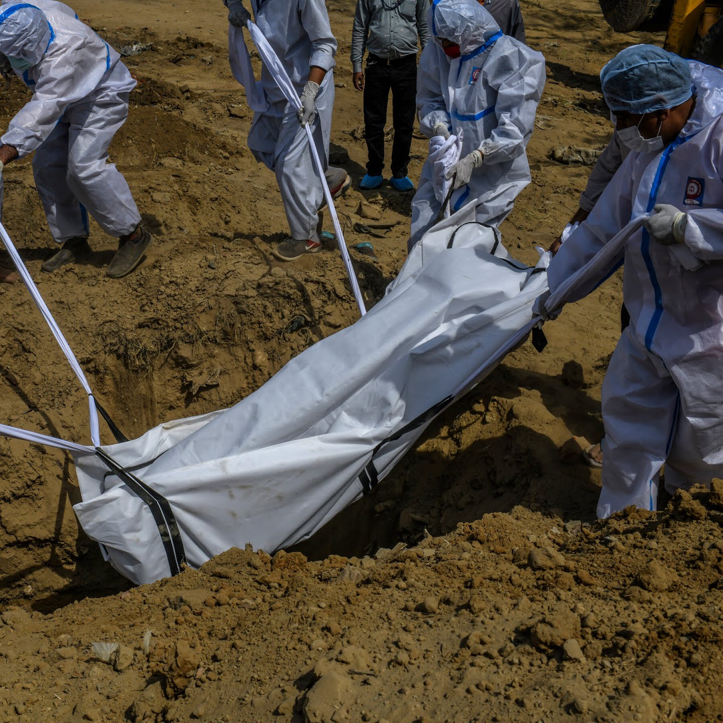 A body is lowered into a grave in New Delhi.