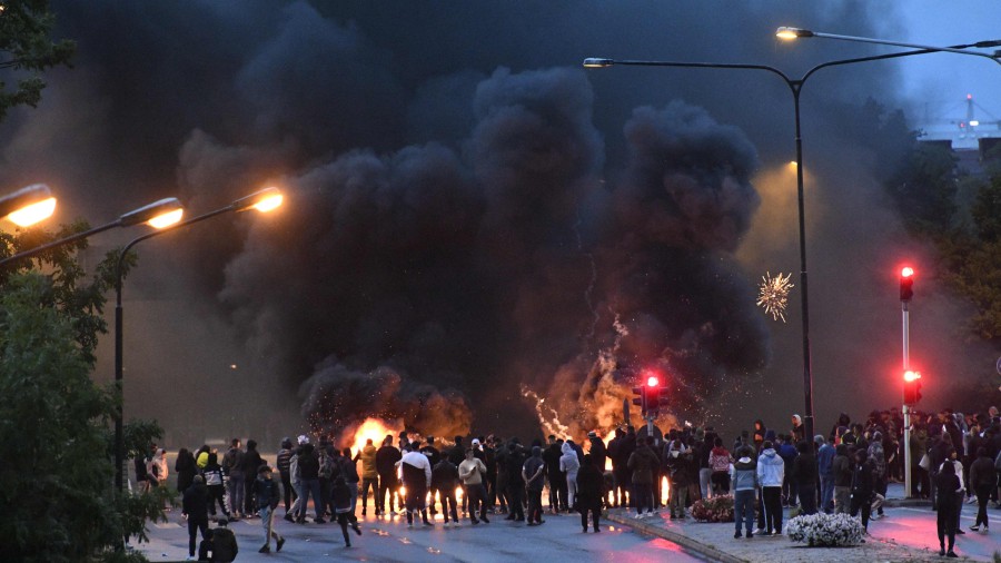 Smoke billows from burning tyres, pallets and fireworks as a few hundred protesters riot in the Rosengard neighbourhood of Malmo, Sweden, on August 28, 2020. - The protest was sparked by the burning of a coran by members of Danish far-right party Stram Kurs earlier in the day. The party's leader Rasmus Paludan was denied entry to Sweden for a manifestation on Friday. (Photo by - / TT News Agency / AFP)'s leader Rasmus Paludan was denied entry to Sweden for a manifestation on Friday. (Photo by - / TT News Agency / AFP)