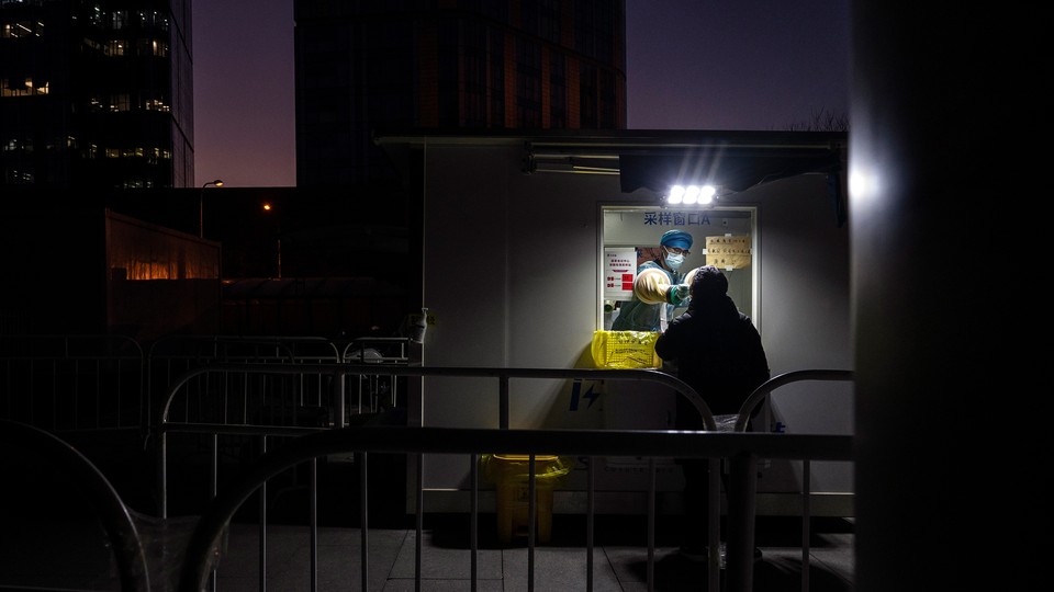 A photograph of a man being given a nucleic acid test for COVID-19 by a health worker at a private testing site in Beijing.