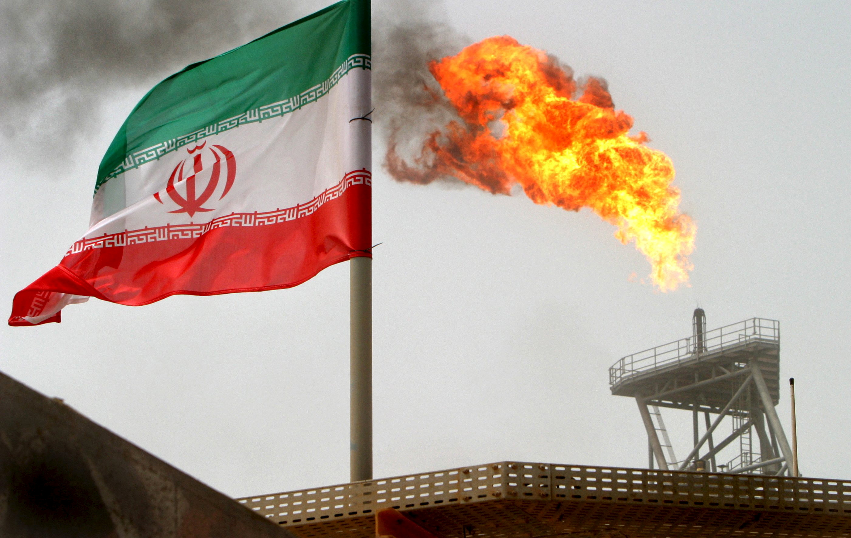 A gas flare on an oil production platform in the Soroush oil fields is seen alongside an Iranian flag in the Gulf