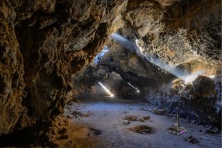 In this artist's impression of the breadcrumb scenario, autonomous rovers can be seen exploring a lava tube after being deployed by a mother rover that remains at the entrance to maintain contact with an orbiter or a blimp.